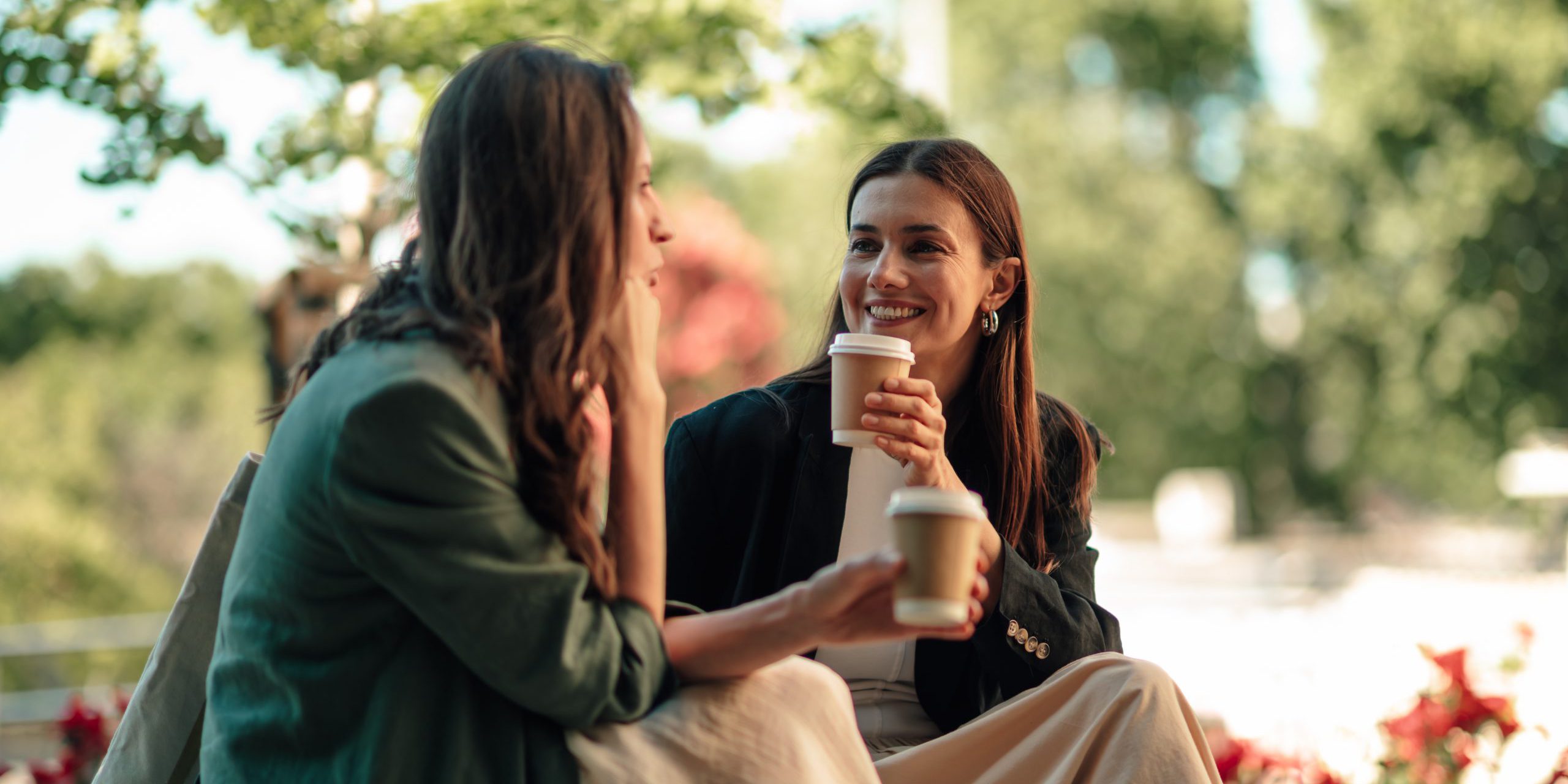 Two,Women,Friends,Engaging,In,A,Lively,Outdoor,Conversation,,Drinking